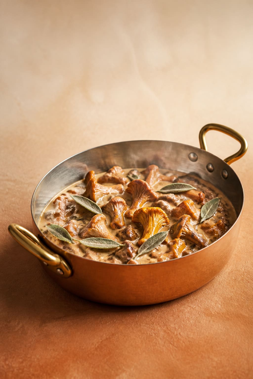 Sautoir en cuivre de girolles et champignons à la crème, feuilles de sauge, vu de trois-quarts