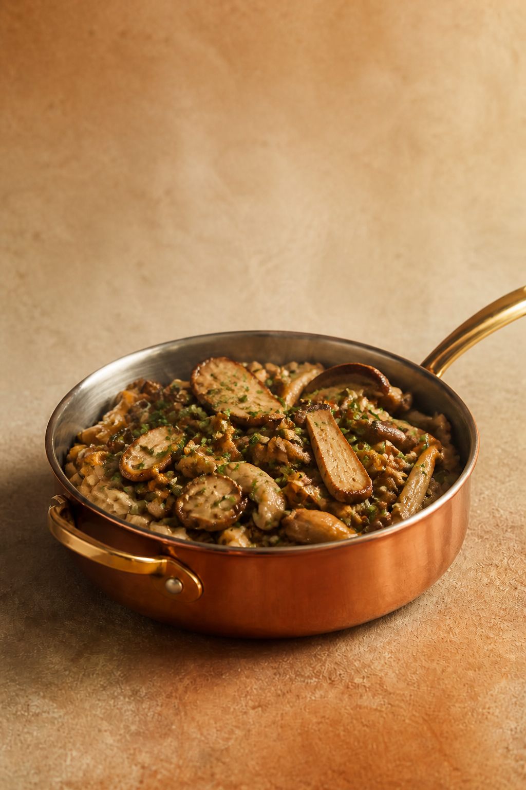 Poêlée de champignons des bois à l’ail et au persil dans une poêle en cuivre, fond beige